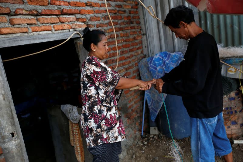 Miskan, a 44-year-old fisherman, is helped by his wife Faridah, 37-year-old, as he prepares to fish at Tambaklorok village in Semarang