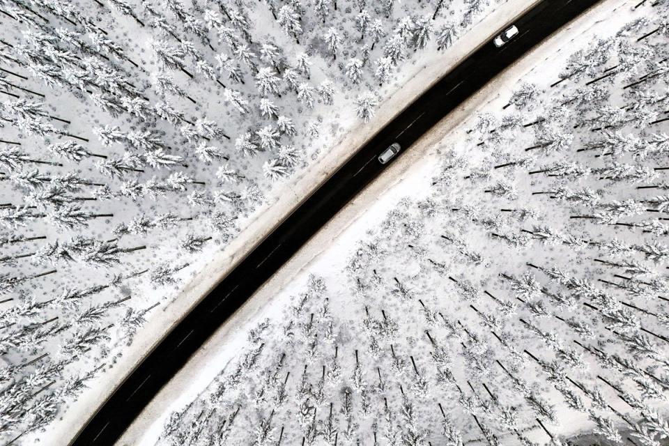 An aerial view shows cars on a road crossing the snow-covered landscape at the Kahler Asten mountain near Winterberg, western Germany on 1 December, 2023 (Getty Images)
