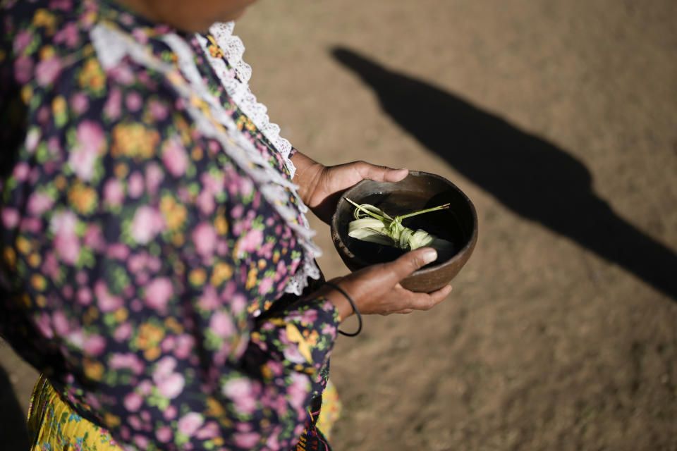 A Raramuri Indigenous woman carries an offering to an altar during a sacred Yumari ceremony to ask for rain and good crops and to honor two local Jesuit priests, Javier Campos and Joaquin Mora, who were murdered in 2022 by a gang leader, in Cuiteco, Mexico, Friday, May 10, 2024. Among the inhabitants of the Tarahumara mountains, especially among the Indigenous Raramuri people, priests are often regarded as profoundly beloved figures who fearlessly offer comfort and help. (AP Photo/Eduardo Verdugo)