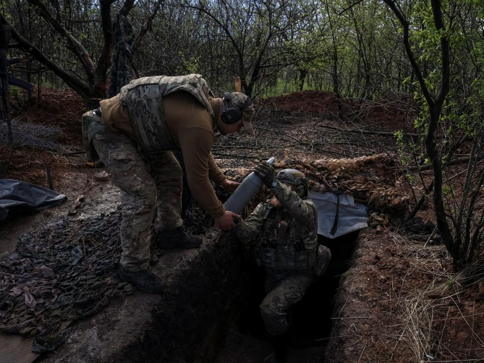 Ukrainian service members from a 3rd separate assault brigade of the Armed Forces of Ukraine, carry a shell as they prepare fire a howitzer D30 at a front line, amid Russia's attack on Ukraine, near the city of Bakhmut, Ukraine April 23, 2023.