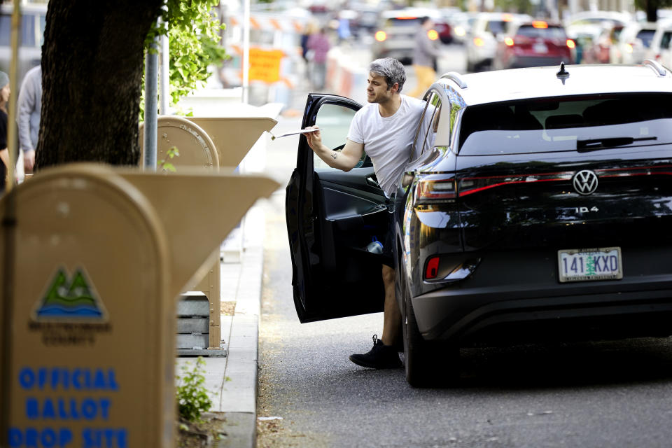 A voter gets out of his car to drop his ballot into a Multnomah County collection box in Portland, Ore., Tuesday May 17, 2022. The state is holding its primary elections. (AP Photo/Craig Mitchelldyer)