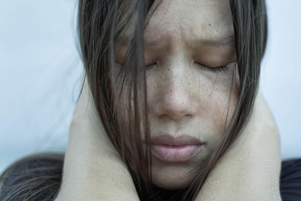 An up-close photo of a girl holding her head looking sad