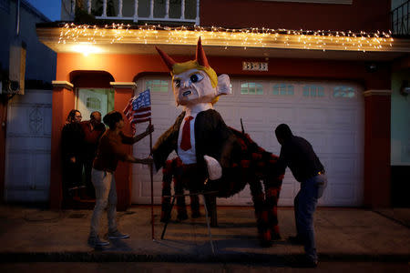 Men fix a pinata representing U.S. President-elect Donald Trump as a devil outside a house before it is set on fire at the traditional Burning of the Devil festival, ahead of Christmas in Guatemala City, Guatemala, December 7, 2016. REUTERS/Luis Echeverria