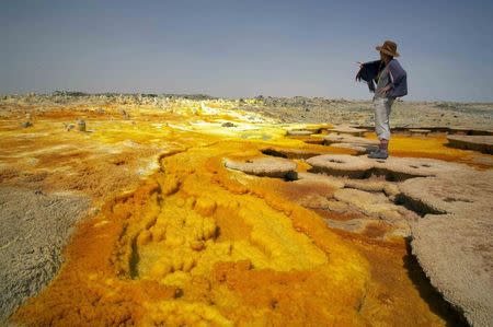 A tourist walks along sulphur and mineral salt formations created by the upwelling springs of Dallol volcano in this January 29, 2007 file photo. REUTERS/Michel Laplace-Toulouse/Files