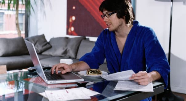 Young man wearing robe, paying bills online