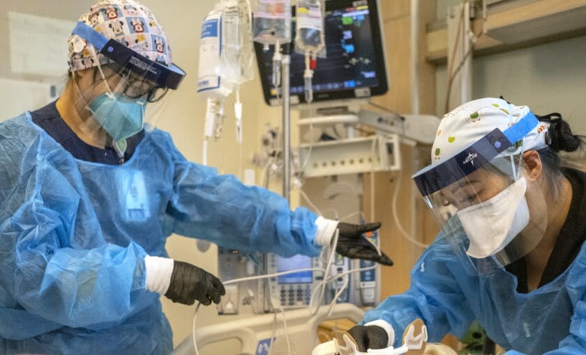 LOS ANGELES, CA - DECEMBER 31: Registered nurse Akiko Gordon, left, and Repertory Therapist Janssen Redondo, right, are working inside the ICU with a covid-19 positive patient at Martin Luther King Jr. Community Hospital (MLKCH) on Friday, Dec. 31, 2021 in Los Angeles, CA. (Francine Orr / Los Angeles Times)