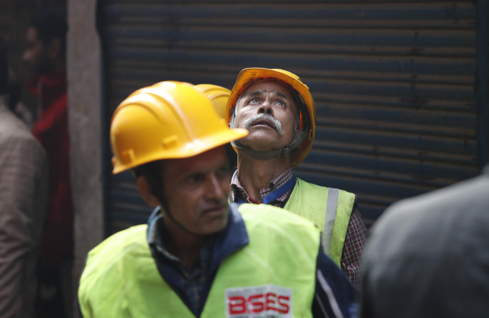 An electricity worker looks at a building which caught fire on Sunday, in New Delhi, India, Monday, Dec. 9, 2019. The victims of a devastating factory fire in central New Delhi early Sunday in which dozens of people died, lived in a dense neighborhood packed with thousands of poor migrant workers from different Indian states forced to live and work in buildings without proper ventilation and prone to fire. (AP Photo/Manish Swarup)