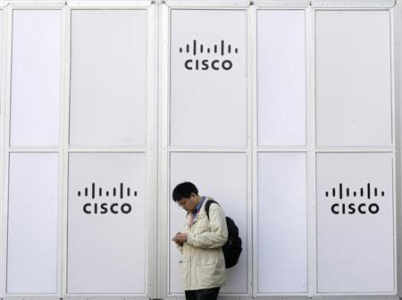 A man looks at his mobile next to a Cisco banner at the Mobile World Congress in Barcelona February 17, 2010. REUTERS/Albert Gea