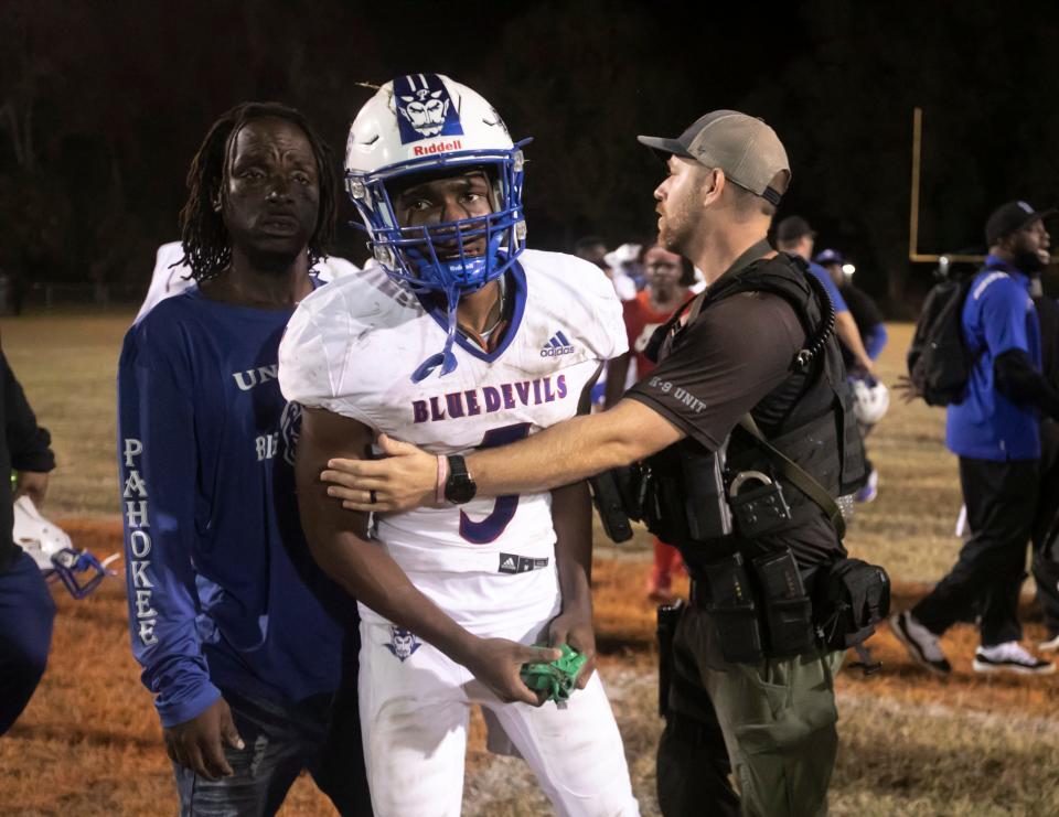 Pahokee's James Jackson (5) gets held back by an Alachua County Sheriffs Deputy during an altercation on the field following Hawthorne's victory in the state regional final last Friday.