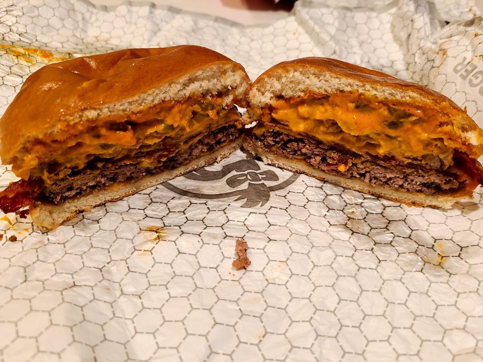 wendys bacon jalepeno cheeseburger cut in half on white wrapper