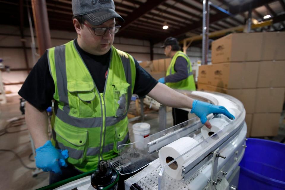 A worker guides toilet paper on a conveyor belt at the Tissue Plus factory, Wednesday, March 18, 2020, in Bangor, Maine. The new company has been unexpectedly busy because of the shortage of toilet paper brought on by hoarders concerned about the coronavirus. (AP Photo/Robert F. Bukaty)