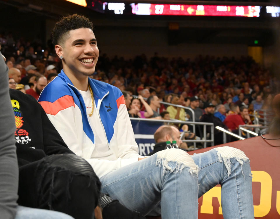 LaMelo Ball sits courtside at a college basketball game.