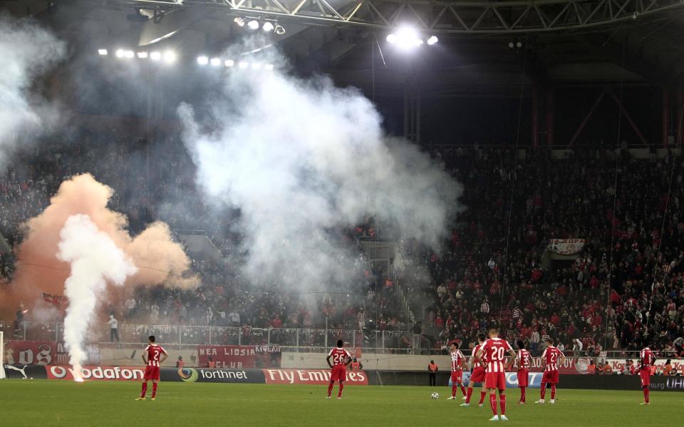 Olympiakos' players wait to continue the game after Panathinaikos' third goal during a Greek League soccer match at Georgios Karaiskakis stadium, in Piraeus port, near Athens, on Sunday, March 2, 2014. Olympiakos’ undefeated run ended after a 3-0 home defeat by Panathinaikos. Very little soccer was played in the last 12 minutes, as Olympiakos fans kept throwing flares and projectiles after they had a penalty awarded in their favor. (AP Photo/Thanassis Stavrakis)