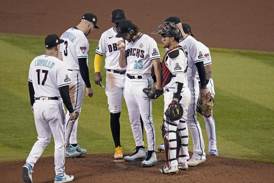 Arizona Diamondbacks starting pitcher Zac Gallen (23) waits to hand the baseball to manager Torey Lovullo (17) during the seventh inning in Game 5 of the baseball World Series against the Texas Rangers Wednesday, Nov. 1, 2023, in Phoenix. (AP Photo/Gregory Bull)