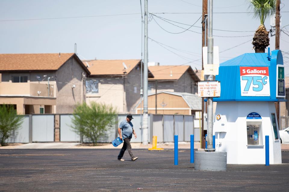 A man carries an empty jug to be filled at a water station at the corner of Van Buren Street and 33rd Avenue in Phoenix on July 15, 2020.