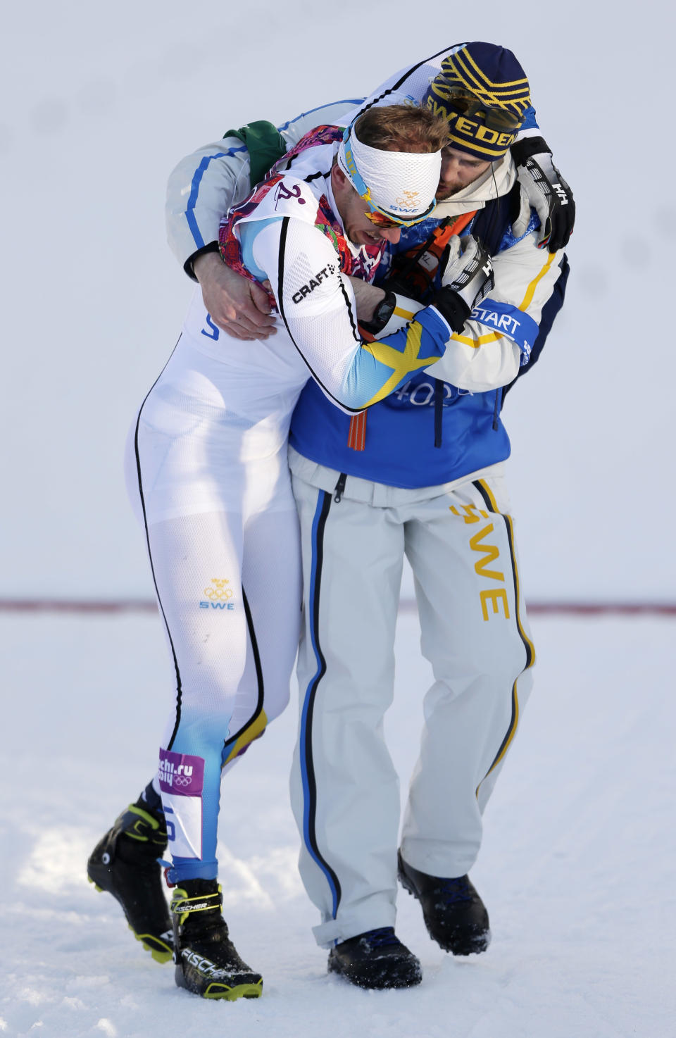 Sweden's Emil Joensson, left, gets assistance after the men's final of the cross-country sprint at the 2014 Winter Olympics, Tuesday, Feb. 11, 2014, in Krasnaya Polyana, Russia. (AP Photo/Matthias Schrader)