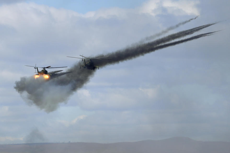 FILE - In this Thursday, Sept. 13, 2018 file photo, military helicopters fire weapons about 250 kilometers (156 miles) north of the city of Chita during the Vostok military exercises in Eastern Siberia, Russia. The weeklong maneuvers span vast expanses of Siberia and the Far East, the Arctic and the Pacific Oceans. They involve nearly 300,000 Russian troops along with 1,000 Russian aircraft and 36,000 tanks and other combat vehicles. (AP Photo/Sergei Grits)
