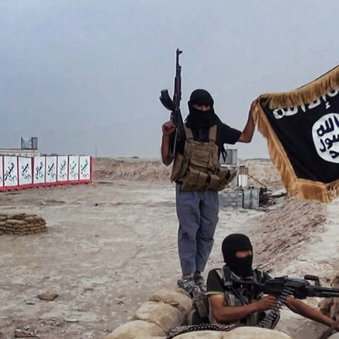 Isil militants pose with the jihadists' flag after they seized an Iraqi army checkpoint in the northern Iraqi province of Salahuddin in 2014 - Credit: AFP