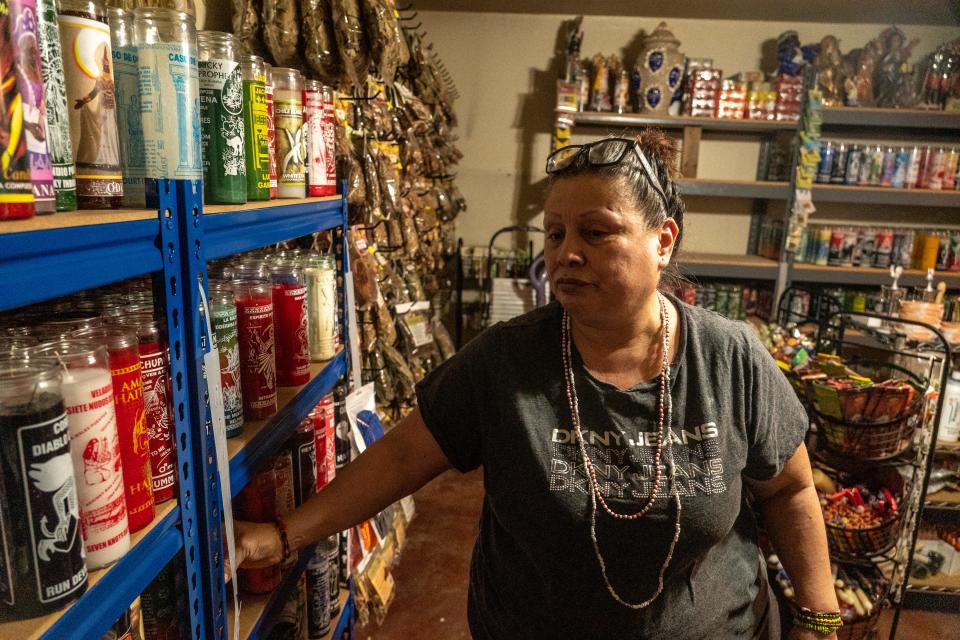 Vicky Hughes of Yerberia Amor Y Paz explains the uses of various candles at her shop in Phoenix on June 7, 2023.