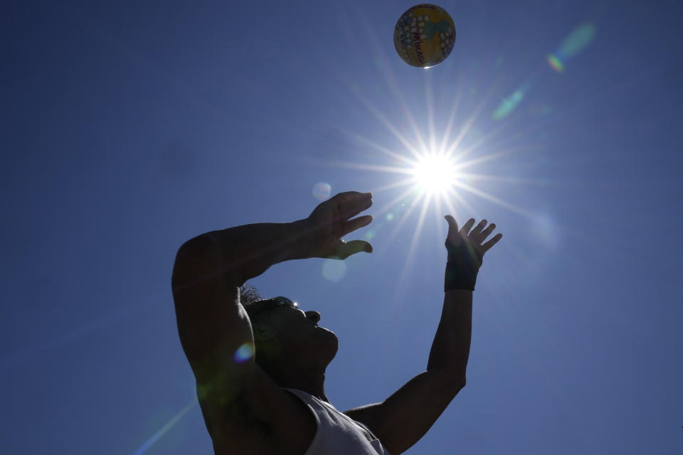 A man plays with a ball at Bondi Beach in Sydney, Tuesday, Sept. 19, 2023. Sydney has experienced its first total fire ban in almost three years and several schools on the New South Wales state South Coast were closed because of a heightened wildfire danger with extraordinarily high temperatures across southeast Australia. (AP Photo/Rick Rycroft)