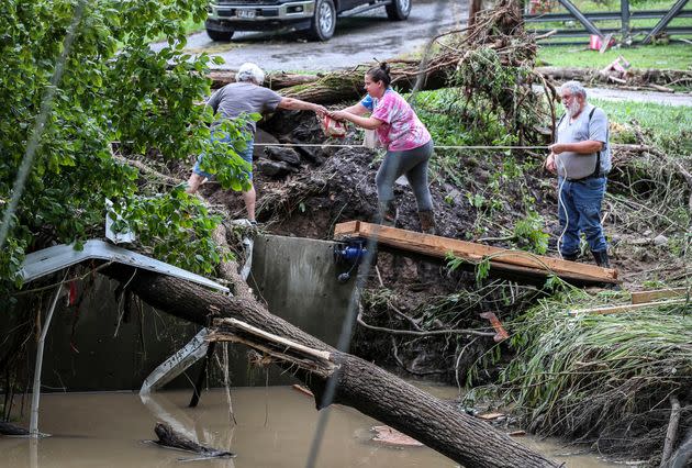 Tonya Smith, whose trailer was washed away by flooding, reaches for food from her mother Ollie Jean Johnson to give to Smith's father, Paul Johnson, as the trio used a rope to hang on over a swollen Grapevine Creek in Perry County, Kentucky, on July 28. (Photo: Matt Stone/USA Today Network/REUTERS)