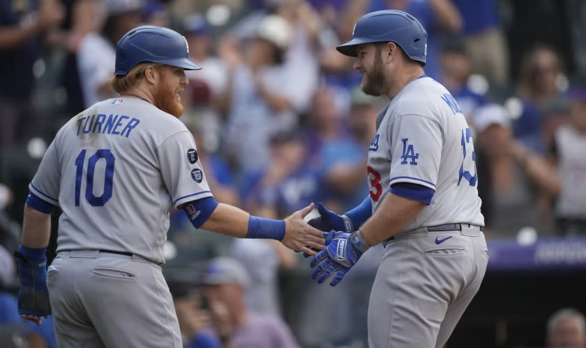 Los Angeles Dodgers' Justin Turner, left, congratulates Max Muncy who crossed home plate following his two-run home run off Colorado Rockies relief pitcher Lucas Gilbreath in the 10th inning of a baseball game Thursday, Sept. 23, 2021, in Denver. (AP Photo/David Zalubowski)