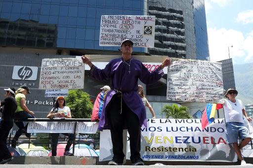 Un hombre protesta en una cruz de madera con carteles contra el gobierno del presidente de Venezuela Nicolás Maduro, en Caracas, el 20 de abril de 2014. (AFP | Juan Barreto)