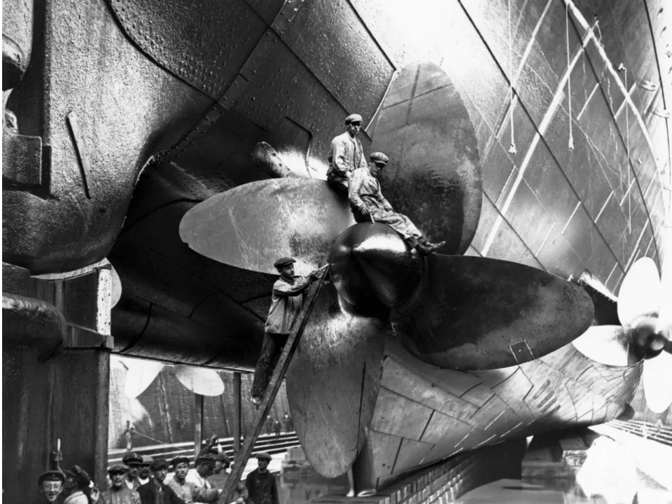 Männer arbeiten an den Propellern der RMS Mauretania. - Copyright: Firmin/Topical Press Agency/Getty Images