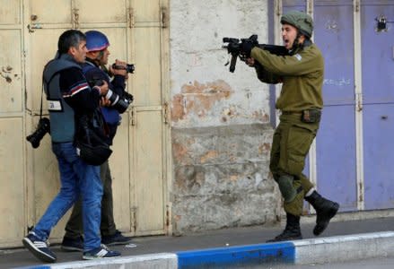 FILE PHOTO: An Israeli soldier shouts as he aims his weapon during clashes with Palestinian demonstrators at a protest against U.S. President Donald Trump's decision to recognise Jerusalem as the capital of Israel, in the West Bank city of Hebron December 15, 2017. REUTERS/Mussa Qawasma/File Photo