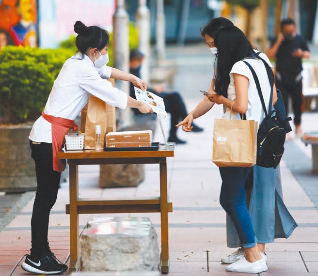 圖為信義商圈的美食商店，店員直接將攤位擺在人行道上以招攬顧客。(季志翔攝)