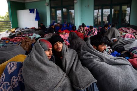 Refugees and migrants try to warm themselves as they take a break at a petrol station before abandoning their trek to the Hungarian border, in the town of Indjija, Serbia October 5, 2016. REUTERS/Marko Djurica