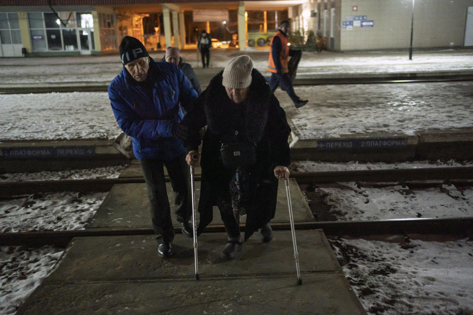 A man helps a woman as they walk toward an evacuation train at a railway station in Sumy, Ukraine, Thursday, Nov. 23, 2023. An average of 80-120 people return daily to Ukraine from territories held by Russia through an unofficial crossing point between the two countries amid a brutal war. Most choose this challenging path, even in freezing temperatures, to escape Russian occupation and reunite with their relatives in Ukraine. (AP Photo/Hanna Arhirova)