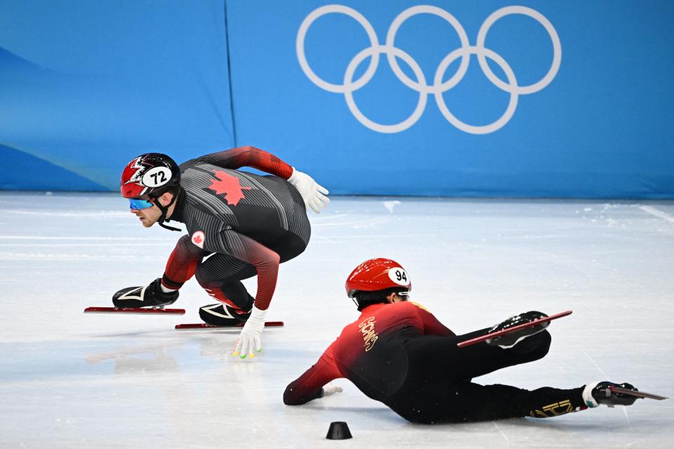 China's Li Wenlong falls behind Canada's Pascal Dion in a semi-final heat of the men's 5000m relay short track speed skating event during the Beijing 2022 Winter Olympic Games at the Capital Indoor Stadium in Beijing on February 11, 2022. (Photo by Anne-Christine POUJOULAT / AFP) (Photo by ANNE-CHRISTINE POUJOULAT/AFP via Getty Images)