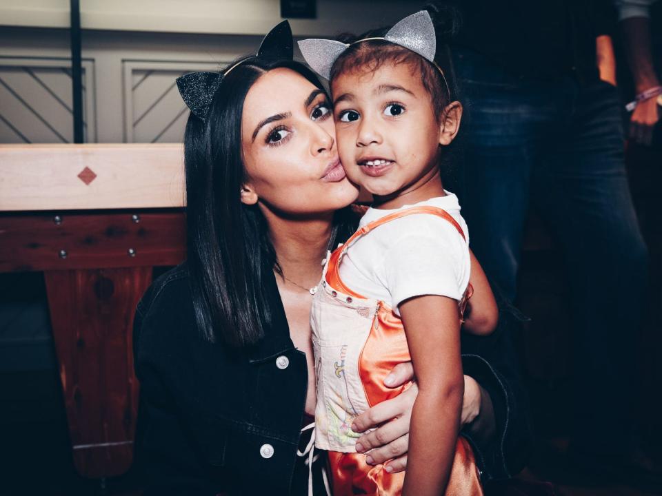 Kim Kardashian with her daughter, North. Both wear headbands with cat ears.