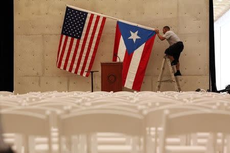 A worker takes off U.S and Puerto Rican flag in San Juan, Puerto Rico, May 16, 2016. REUTERS/Alvin Baez