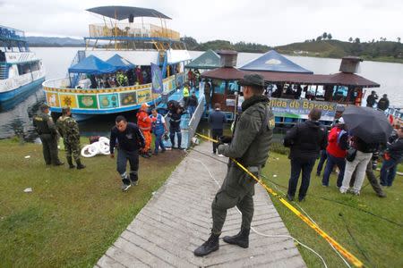 A police officer holds onto a yellow tape as fellow police officers and rescue workers continue with the search for people believed to be missing after a tourist boat sank on Sunday, in Guatape, Colombia June 26, 2017. REUTERS/Fredy Builes