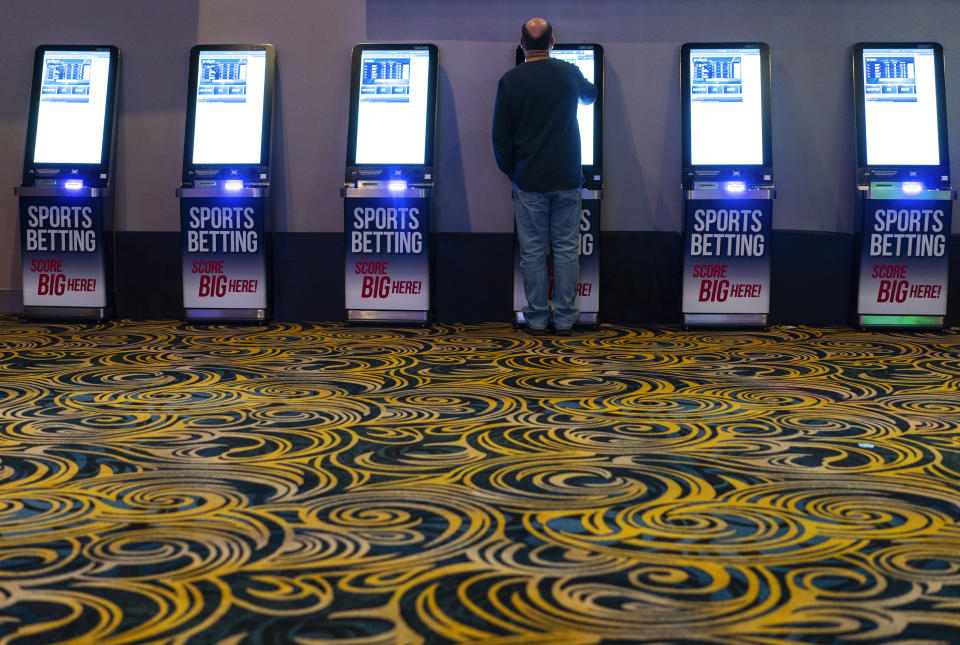 A man navigates a sports betting kiosk at Turfway Park Racing & Gaming, Friday, Dec. 22, 2023, in Florence, Ky. Sports betting has spread rapidly across U.S. states in the past five years. But the odds for further expansion may be fading as state legislatures prepare to return to work in 2024. (AP Photo/Carolyn Kaster)