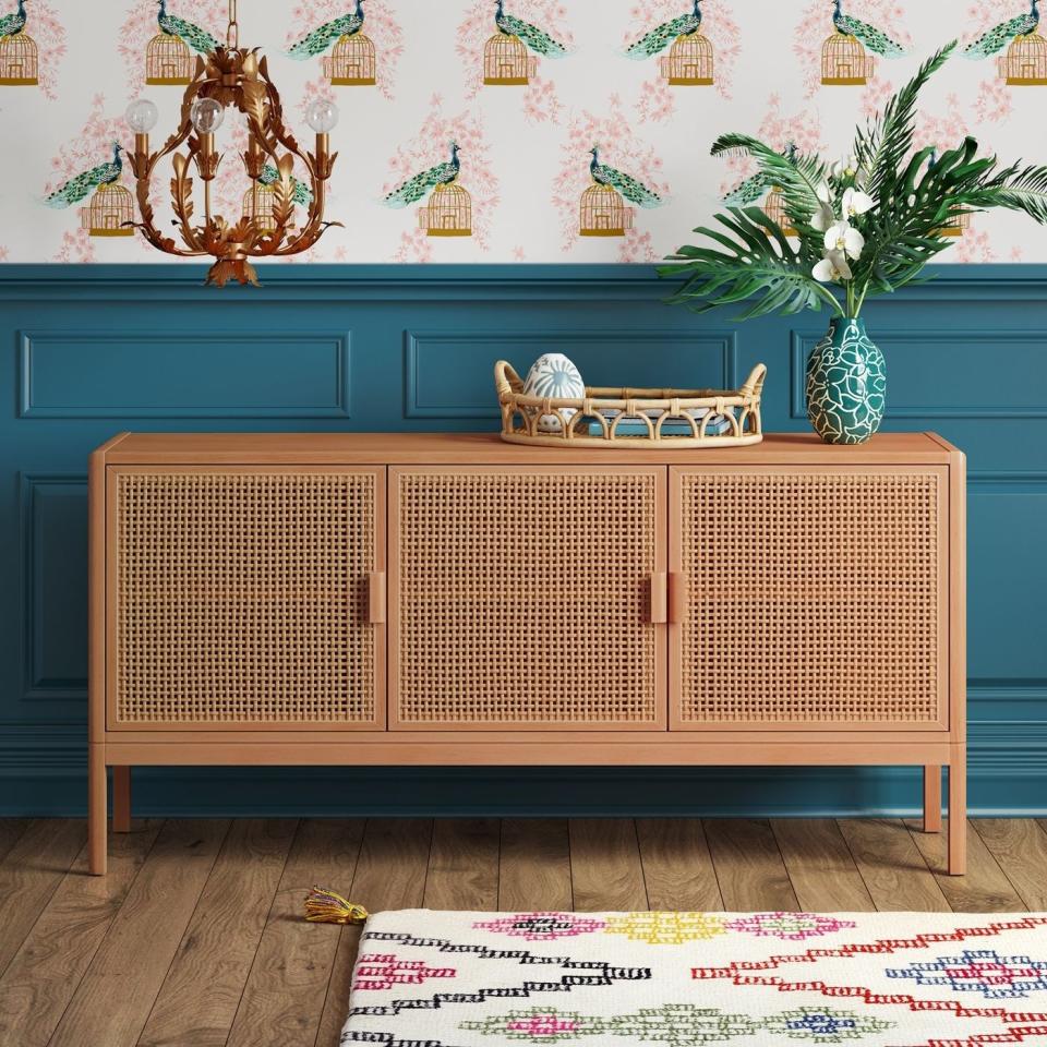 the rattan tv stand in natural brown against a teal wall