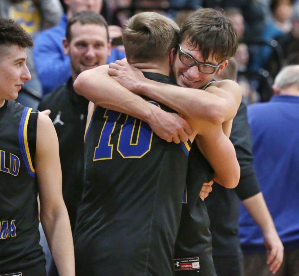 Oakfield-Alabama's senior captain Kameron Cusmano (3), right, hugs teammate Gaige Armbrewster (10) as players celebrate on the sidelines as time runs down in their Section V Class C2 championship final against Lyons Friday, March 4, 2022 at Victor High School.  Oakfield-Alabama captured the C2 Championship 55-29. 