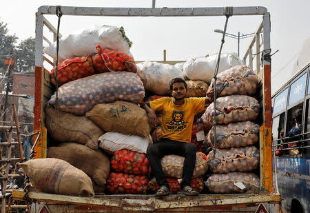 A man sits on sacks filled with onions and potatoes on a truck parked at a roadside in New Delhi, India, October 5, 2018. REUTERS/Anushree Fadnavis