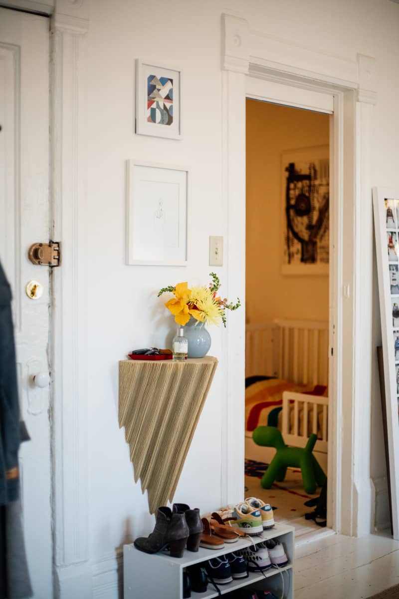 Floral arrangement and room spray displayed on surface near apartment entrance.