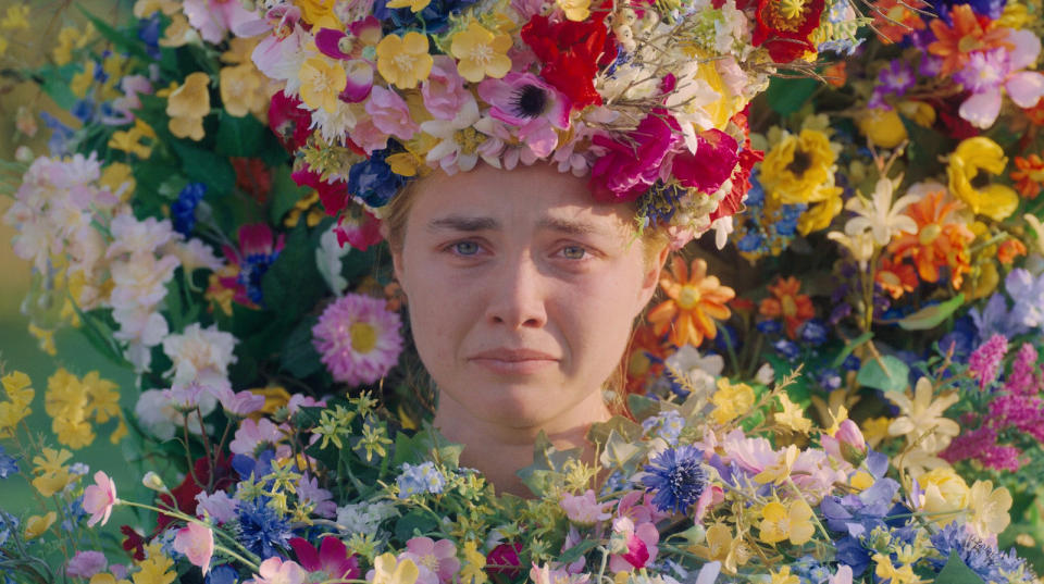 Florence Pugh wearing a flower crown and a flower dress with a frown on her face at the end of 'Midsommar'