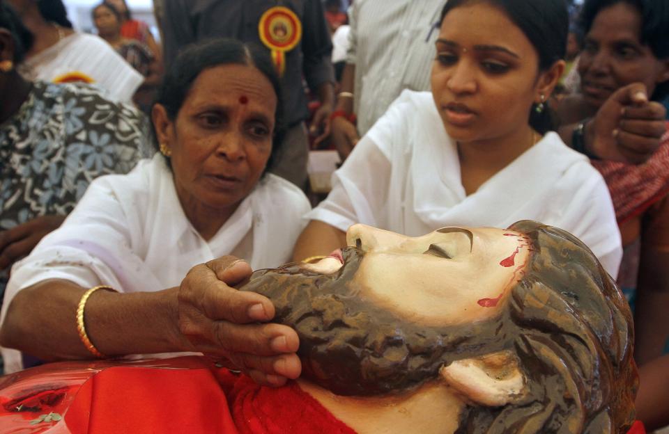 A Catholic devotee touches a statue of Jesus Christ to get blessings during Good Friday prayers at a church in Chennai