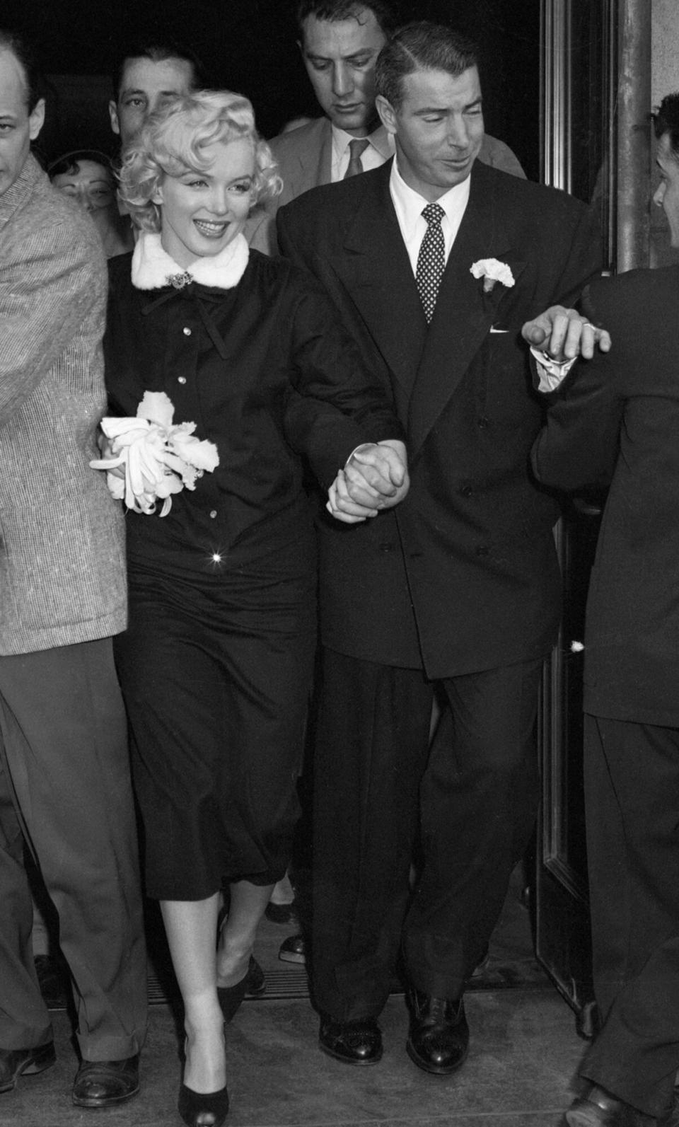 Marilyn Monroe and former Yankee great Joe Di Maggio press through a crowd of newsmen after their marriage in the office of Municipal Judge Charles Peery in San Francisco City Hall January 14