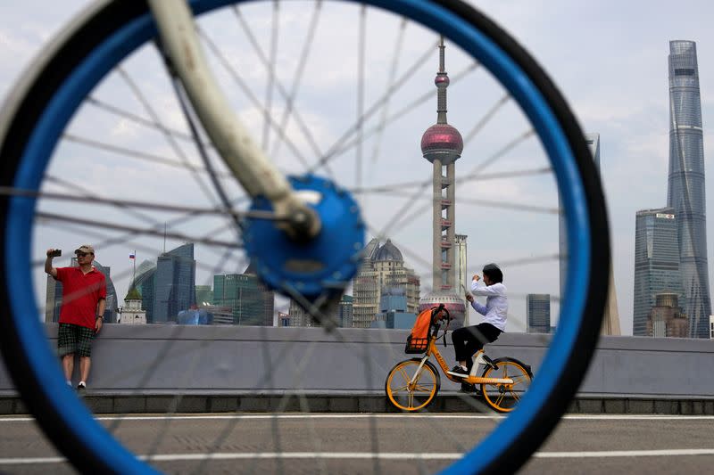 People ride bicycles in front of Lujiazui financial district, following the coronavirus disease (COVID-19) outbreak, in Shanghai