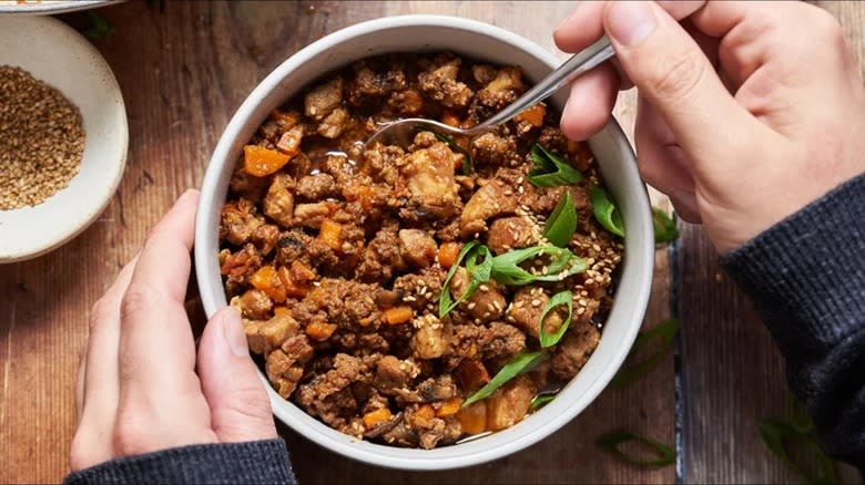 hands holding a bowl of chili