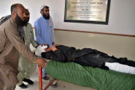 People transport a man injured in a bus accident in Dana Sar, Khyber Pakhtunkhwa province, at a hospital in Quetta, Pakistan, Sunday, July 3, 2022. An official said the passenger bus slid off a mountain road and fell 200 feet (61 meters) into a ravine in heavy rain killing at least 18 people and injuring some 12 others. (AP Photo/Arshad Butt)