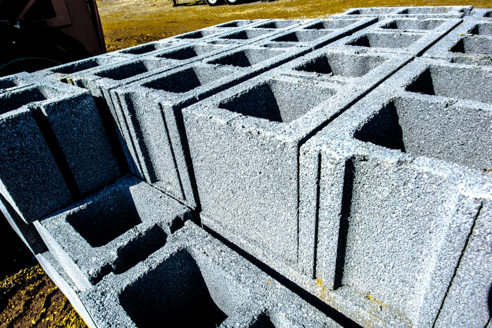 A stack of cinder blocks neatly arranged in rows outside on the ground