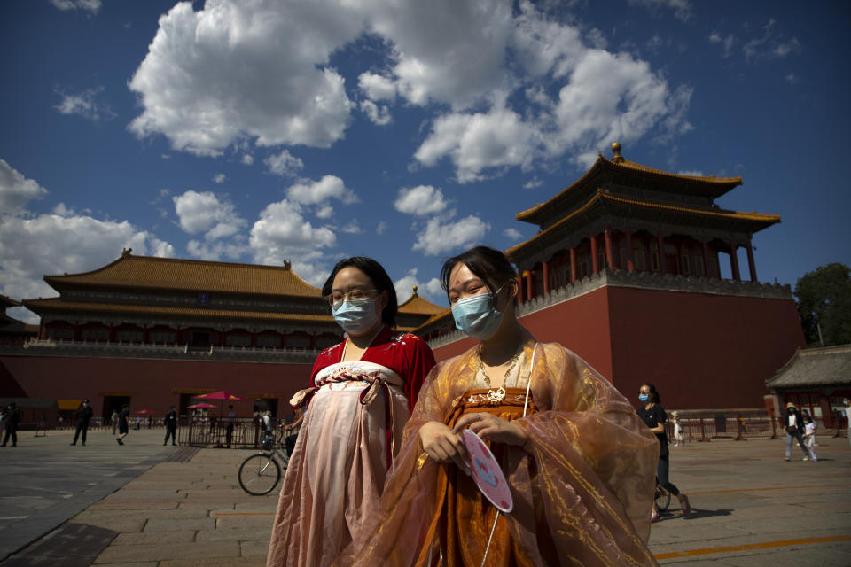 Women in period dress and wearing face masks to protect against the new coronavirus walk outside the entrance to the Forbidden City in Beijing, Wednesday, May 27, 2020. The Chinese People's Political Consultative Conference (CPPCC) concluded its session in Beijing on Wednesday, part of the annual meetings of China's two top legislative bodies. (AP Photo/Mark Schiefelbein)