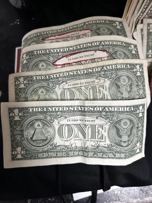 A stack of US one-dollar bills with "In God We Trust" circled